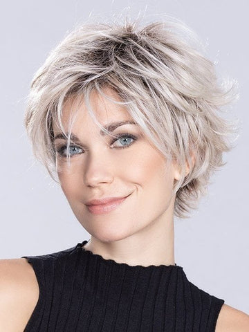 Model wearing short layered synthetic wig in ash blonde with textured tousled pixie cut