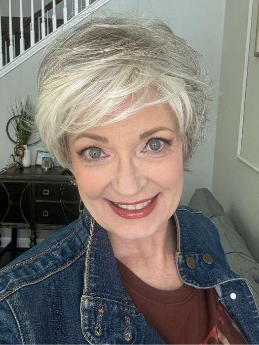 Smiling woman wearing a short layered synthetic wig in silver white styled pixie with side bangs